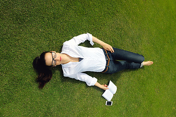 Image showing Young woman reading a book in the park