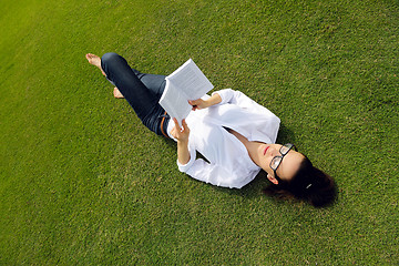 Image showing Young woman reading a book in the park