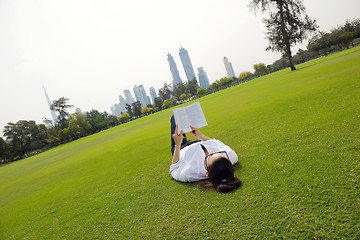 Image showing Young woman reading a book in the park