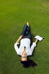 Image showing Young woman reading a book in the park