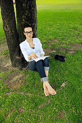 Image showing Young woman reading a book in the park