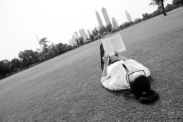 Image showing Young woman reading a book in the park