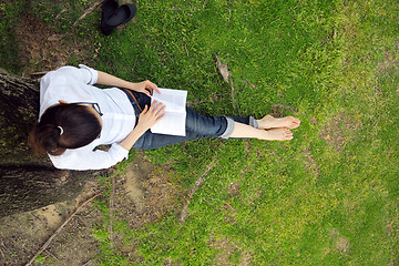 Image showing Young woman reading a book in the park