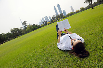 Image showing Young woman reading a book in the park