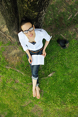 Image showing Young woman reading a book in the park