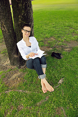 Image showing Young woman reading a book in the park