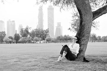 Image showing Young woman reading a book in the park