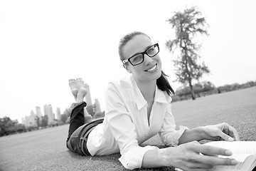 Image showing Young woman reading a book in the park