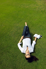 Image showing Young woman reading a book in the park