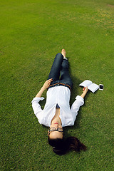 Image showing Young woman reading a book in the park