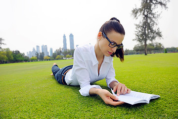 Image showing Young woman reading a book in the park