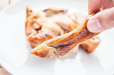 Image showing Hand on grilled chicken leg