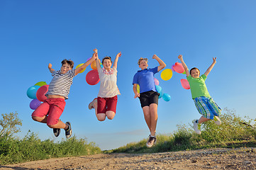 Image showing happy children jumping on field with balloons