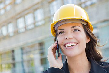 Image showing Young Female Contractor Wearing Hard Hat on Site Using Phone
