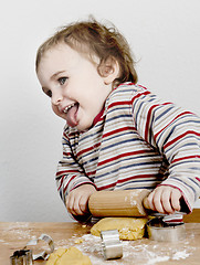 Image showing happy young child with rolling pin in grey background