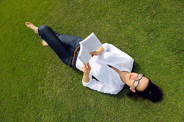 Image showing Young woman reading a book in the park