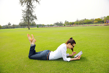 Image showing Beautiful young woman with  tablet in park