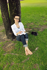 Image showing Young woman reading a book in the park