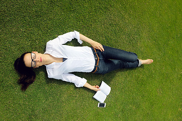 Image showing Young woman reading a book in the park