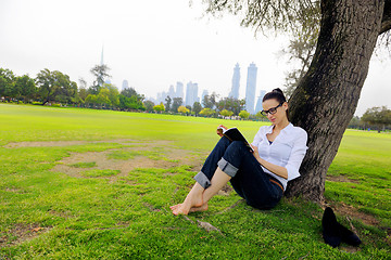 Image showing Young woman reading a book in the park