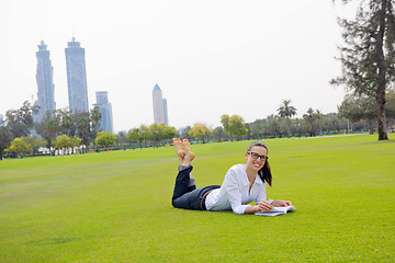 Image showing Young woman reading a book in the park