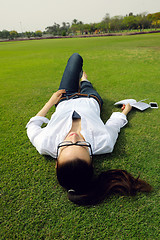 Image showing Young woman reading a book in the park