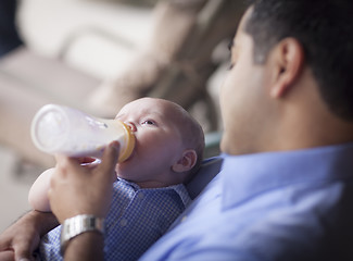 Image showing Happy Hispanic Father Bottle Feeding His Mixed Race Son