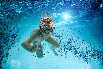 Image showing Teenager in the mask and snorkel swim underwater.