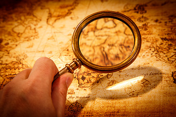 Image showing Vintage magnifying glass lies on an ancient world map