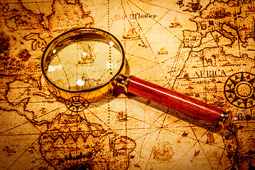 Image showing Vintage magnifying glass lies on an ancient world map