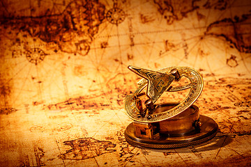 Image showing Vintage compass lies on an ancient world map.