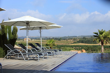 Image showing Wooden deck with recliners and umbrellas