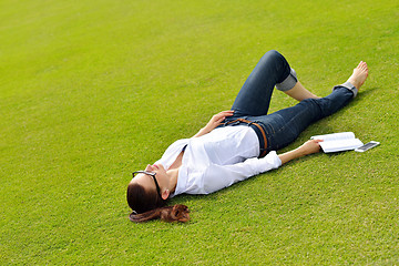 Image showing Young woman reading a book in the park