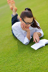 Image showing Young woman reading a book in the park