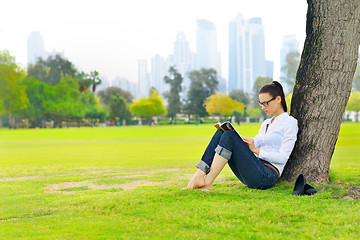 Image showing Young woman reading a book in the park