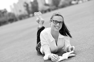 Image showing Young woman reading a book in the park