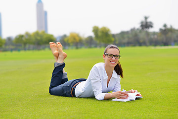 Image showing Young woman reading a book in the park