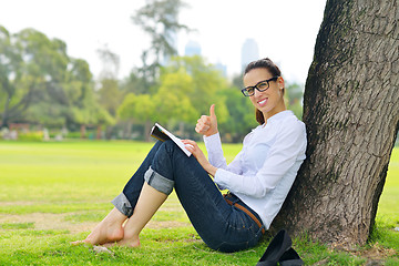 Image showing Young woman reading a book in the park