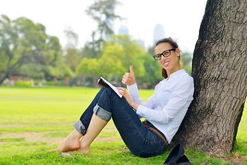 Image showing Young woman reading a book in the park