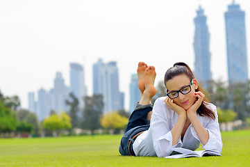 Image showing Young woman reading a book in the park