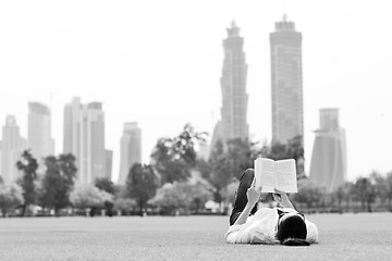 Image showing Young woman reading a book in the park