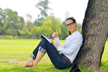 Image showing Young woman reading a book in the park