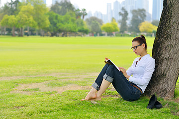 Image showing Young woman reading a book in the park