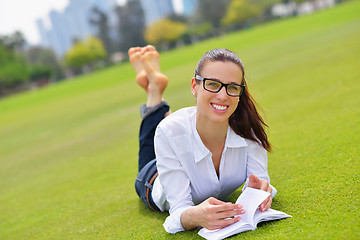 Image showing Young woman reading a book in the park