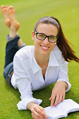 Image showing Young woman reading a book in the park