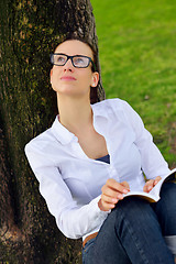 Image showing Young woman reading a book in the park