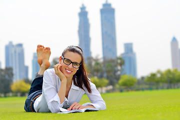 Image showing Young woman reading a book in the park