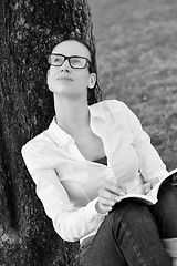 Image showing Young woman reading a book in the park