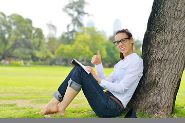 Image showing Young woman reading a book in the park