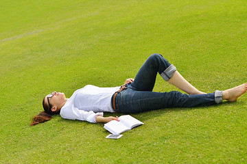 Image showing Young woman reading a book in the park